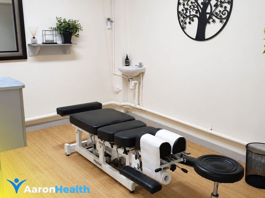 Modern chiropractic treatment room at Aaron Health Bundaberg featuring an adjustment table, consultation stool, and relaxing clinical environment.