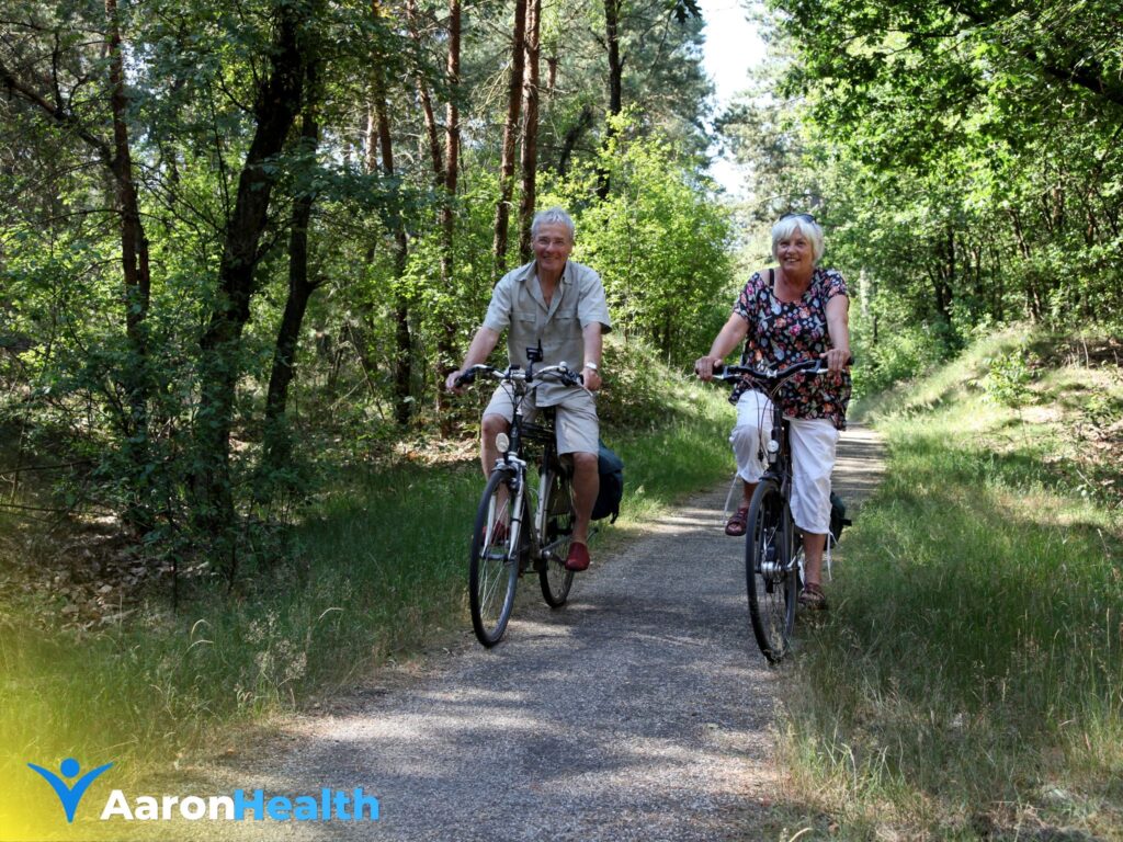 Older couple cycling together on a woodland path